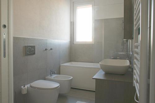 a white bathroom with a toilet and a sink at BnButler - Govone - Ampio e Luminoso Appartamento con Terrazza in Milan