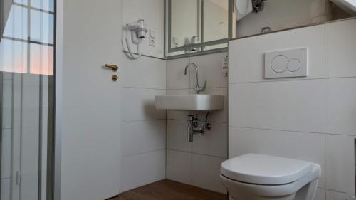 a white bathroom with a toilet and a sink at Hotel Speeter in Weisenheim am Berg