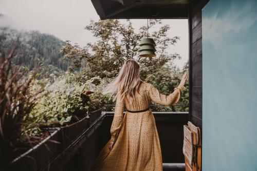 a woman in a long dress looking out a window at SEEBICHL haus am see Designhotel Kitzbühel in Kitzbühel