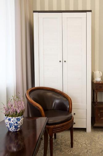 a leather chair sitting next to a table and a cabinet at Kamienica Boutique ApartHotel in Białystok