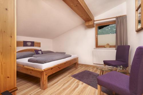 een slaapkamer met een bed en 2 paarse stoelen bij Auszeit-Oetztal in Sautens