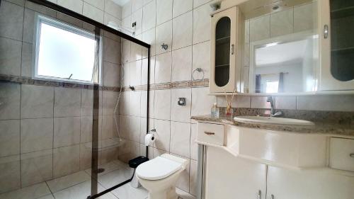 Un baño con inodoro, lavabo y espejo. en Piscina Aquecida, 5 suítes, Bilhar, Varanda Gourmet, 100mts mar, en Itanhaém