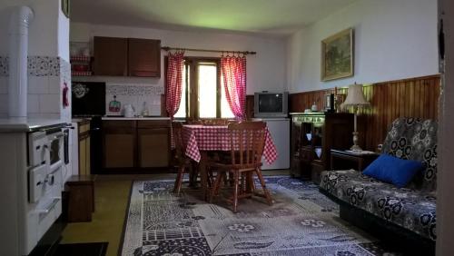 una cucina con tavolo, sedie e divano di Kuća za odmor Kalina a Mokra Gora