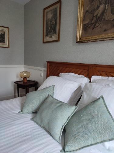 a bed with white sheets and green pillows at Manoir de Daubeuf in Daubeuf-Serville