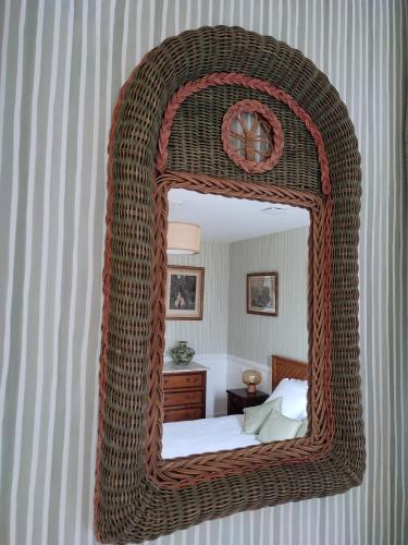 a bedroom with a wicker mirror on the wall at Manoir de Daubeuf in Daubeuf-Serville
