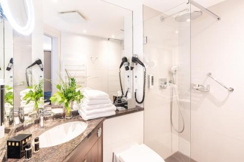 a white bathroom with a sink and a shower at SEETELHOTEL Ostseehotel Ahlbeck in Ahlbeck