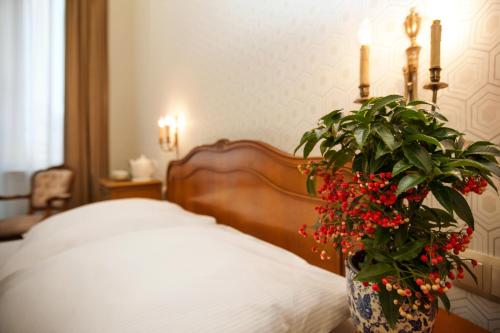 a bedroom with a bed with a vase with red flowers at Kamienica Boutique ApartHotel in Białystok