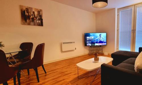 - un salon avec un canapé, une table et une télévision dans l'établissement StayBrum Acadian City Centre Apartments Birmingham Chinatown, à Birmingham
