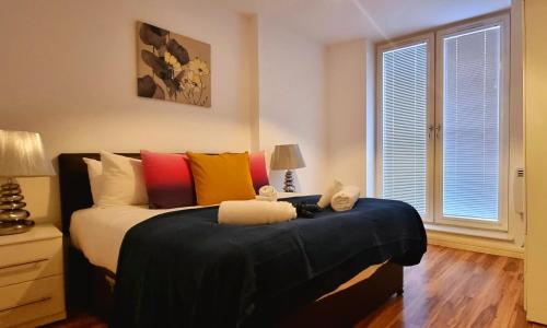 - une chambre avec un lit et des oreillers colorés dans l'établissement StayBrum Acadian City Centre Apartments Birmingham Chinatown, à Birmingham