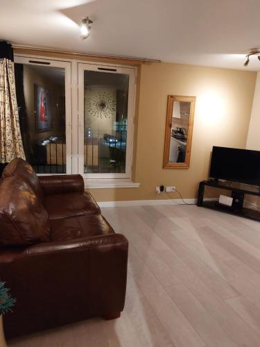 a living room with a brown leather couch and a piano at Church Street Apartments in Inverness