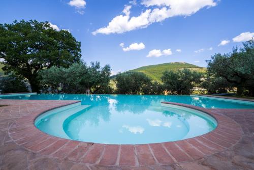 a pool with blue water and mountains in the background at Agriturismo Le Vigne in Foligno