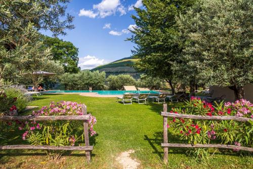 two wooden benches sitting in a yard with flowers at Agriturismo Le Vigne in Foligno