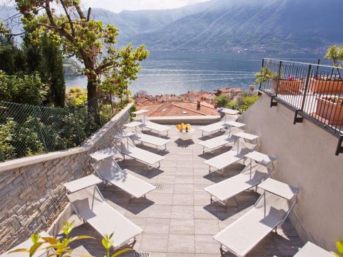 a row of white chairs on a patio overlooking the water at Residence Sala Comacina apartment no 2 with pool and spa by Italian Apartments in Isola Comacina
