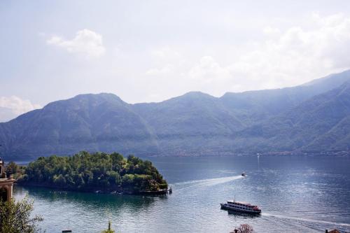 a boat on a lake with mountains in the background at Residence Sala Comacina apartment no 2 with pool and spa by Italian Apartments in Isola Comacina