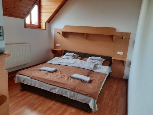 a bedroom with a large bed with two towels on it at Hat Testvér Fogadó in Dömsöd