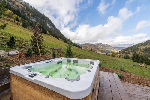 bañera de hidromasaje en una terraza de madera con vistas a la montaña en Le Lodge Rodzina, Luxueux chalet familial entièrement rénové avec Jacuzzi et Vue par LLA Selections en La Clusaz