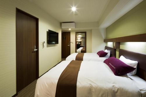 a hotel room with two beds with purple pillows at Green Rich Hotel Kyoto Station South (Artificial hot spring Futamata Yunohana) in Kyoto
