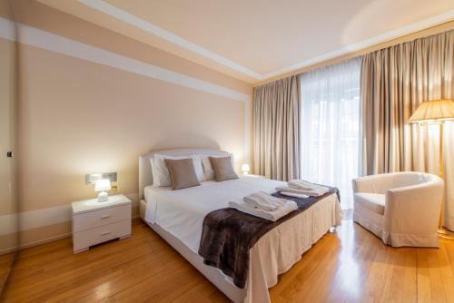 a bedroom with a bed and a chair and a window at Milan Royal Suites - Centro in Milan
