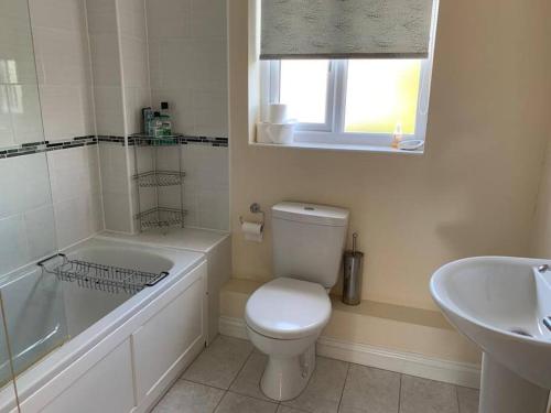 a white bathroom with a toilet and a sink at Cheerful 3 bedroom home close to beach and High St in Sheringham