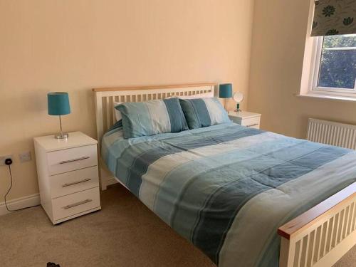 a bedroom with a large bed with a blue comforter at Cheerful 3 bedroom home close to beach and High St in Sheringham