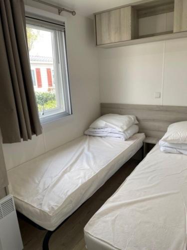 deux lits assis dans une pièce avec une fenêtre dans l'établissement Mobil Home, à Fréjus