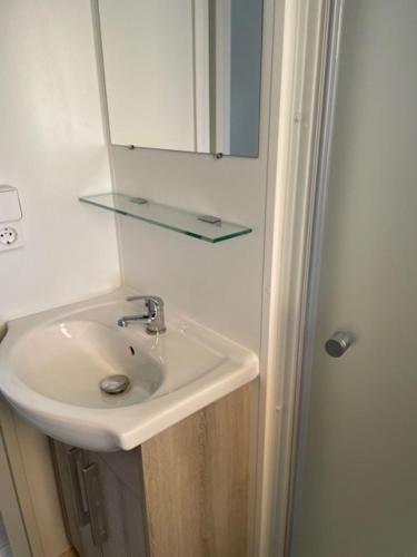 La salle de bains est pourvue d'un lavabo avec miroir et d'une étagère en verre. dans l'établissement Mobil Home, à Fréjus