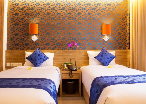 a hotel room with two beds with blue pillows at Natya Hotel Kuta in Kuta