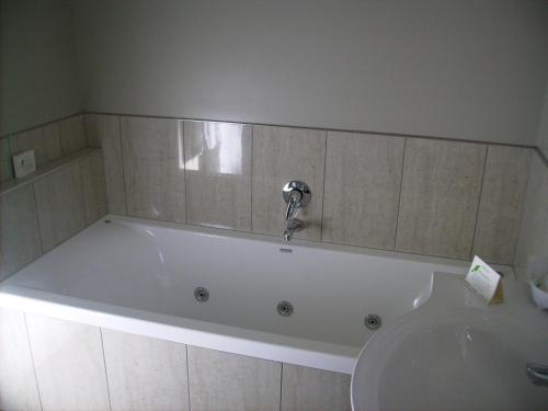 a bath tub with a faucet in a bathroom at Albert Court Motor Lodge in Hamilton