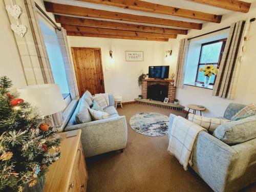 a living room with two couches and a christmas tree at Grosmont Cottage, Ruswarp in Whitby