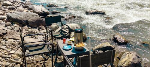 a table with a bowl of food next to the water at Vedant Valley Resort, Kund-Guptkashi, By Himalayan Eco Lodges in Rudraprayāg