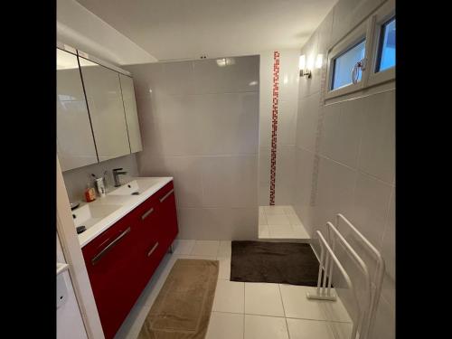 La salle de bains est pourvue d'une armoire rouge et d'un lavabo. dans l'établissement Balaena - maison avec jardin proche plage, à Luc-sur-Mer