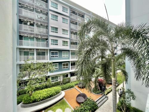 an apartment building with a palm tree in front of it at The trust huahin resort condo greeny room in Hua Hin