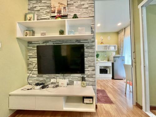 a living room with a tv on a stone wall at The trust huahin resort condo greeny room in Hua Hin