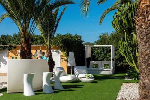 a garden with white chairs and palm trees at Serena Villa in Ibiza Town