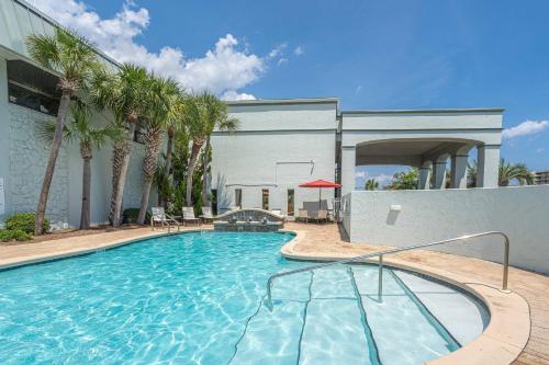 a swimming pool with palm trees and a building at Club Destin Condos in Destin