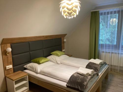 1 dormitorio con 1 cama con sábanas blancas y almohadas verdes en Leśna Polana, en Radawa