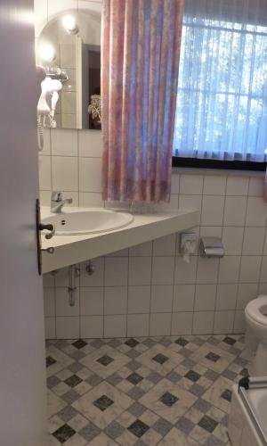 a bathroom with a sink and a toilet at Hotel zur Post Dabringhausen in Wermelskirchen