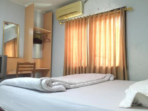 a bedroom with a bed with white sheets and a window at Losmen PUM Syariah at Desa Wisata Sabang in Sabong