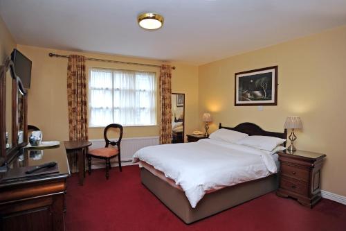 a bedroom with a bed and a desk and a television at Clooneen House in Westport