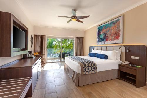 a bedroom with a bed and a flat screen tv at Royalton Splash Punta Cana, An Autograph Collection All-Inclusive Resort & Casino in Punta Cana