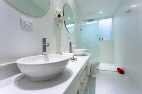 a white bathroom with a sink and a mirror at Le Cameleon Boutique Hotel in Puerto Viejo