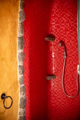 a shower with a red wall with a shower head at Villa Orpheus Santorini in Megalokhori