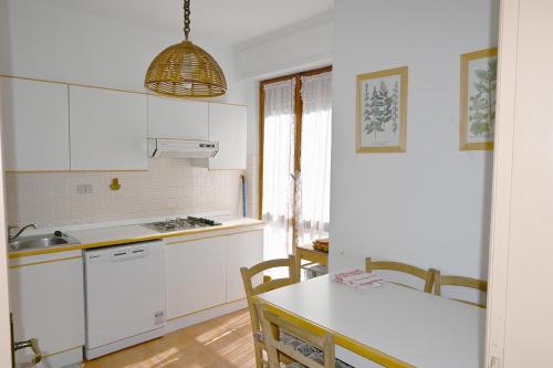 una cocina con armarios blancos y una mesa con sillas. en Bardonecchia Appartamento XL en Bardonecchia