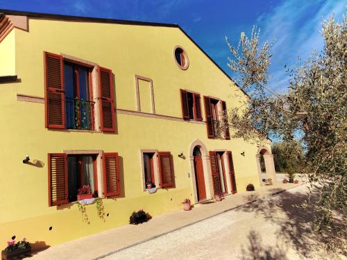 a yellow building with red shutters on it at IL VILLAGGIO DELLE FATE in Macerata