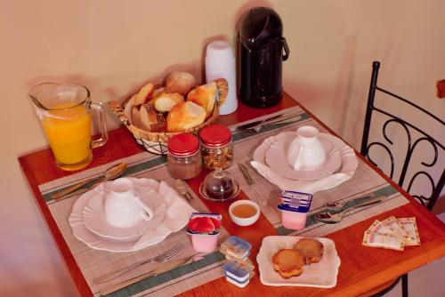 a table with plates and cups and a basket of bread at Verde da Mantiqueira Chalés in Visconde De Maua