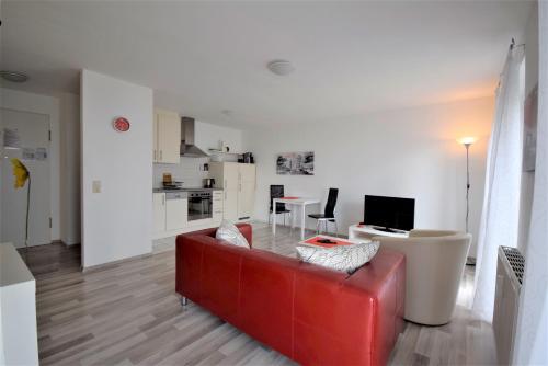 ein Wohnzimmer mit einem roten Sofa und einer Küche in der Unterkunft Naherholung Ferienwohnung Bad Säckingen in Bad Säckingen