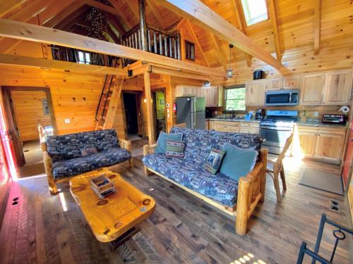 a living room with a couch and a table in a cabin at BC Log cabin with private beach river fire pit AC wifi onsite trails ski slope views in Carroll