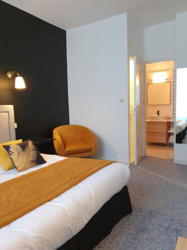 a hotel room with a bed and a chair at Hôtel Le Rohan Charme et Caractère in Pontivy