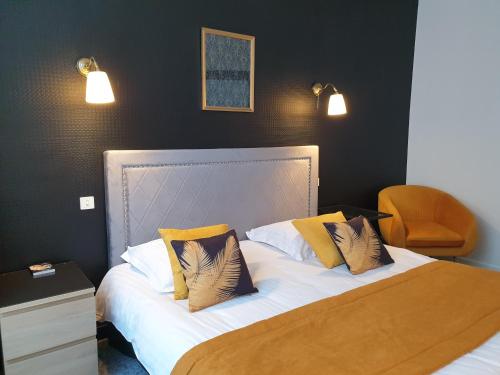 a bedroom with a bed with yellow and white pillows at Hôtel Le Rohan Charme et Caractère in Pontivy