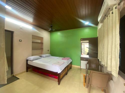 a bedroom with a bed and a green wall at Manasa guest House in Hampi